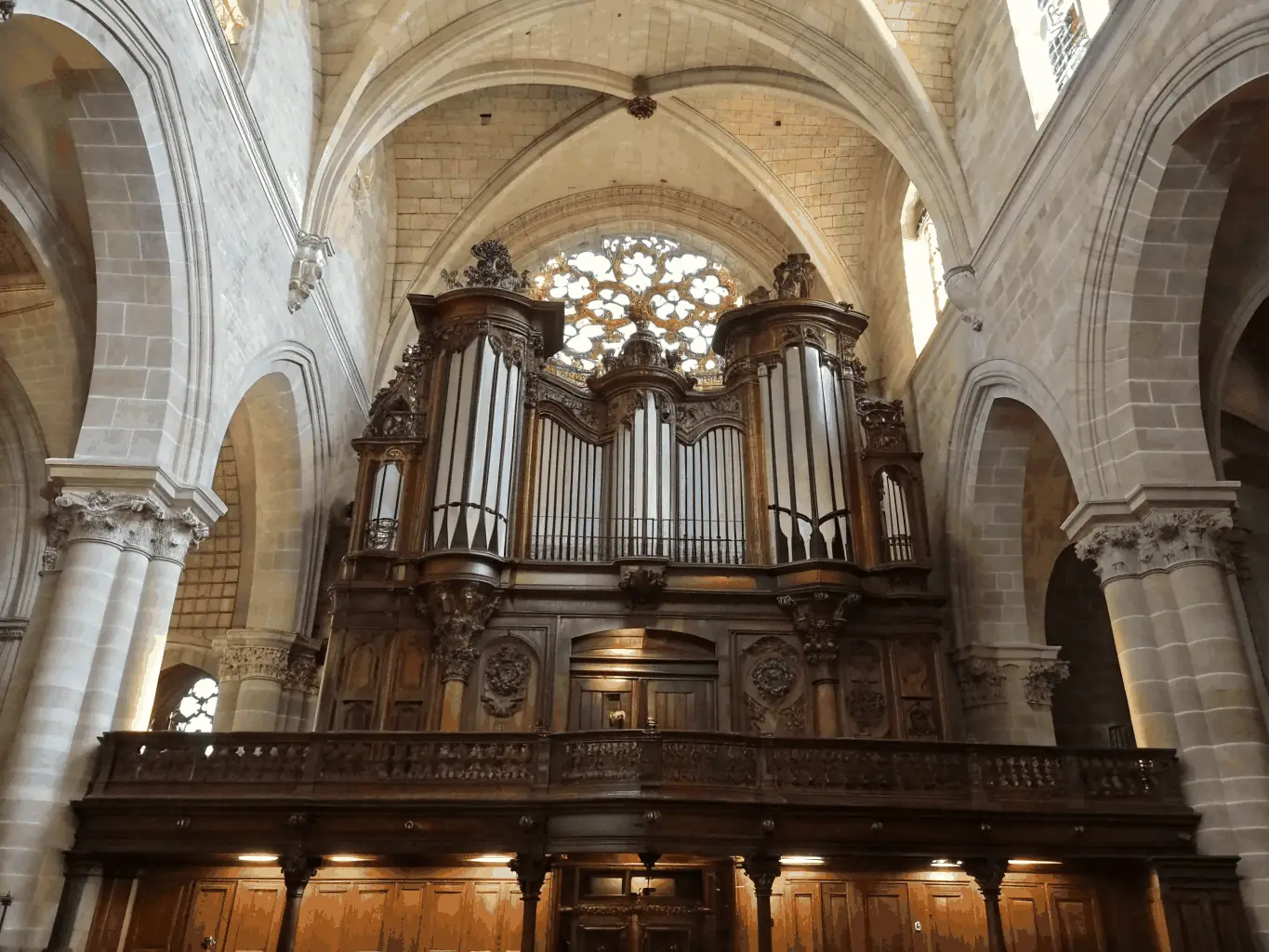 A beautifully restored historic organ in a French church, bathed in soft light, showcasing the intricate details of its pipes and casework.